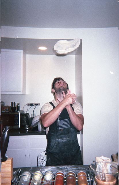 Moisey tossing pizza dough in his kitchen